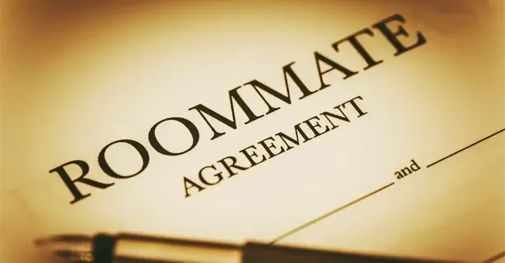 Paper with text "roommate agreement" typed on it and spaces for two people's names with pen on it