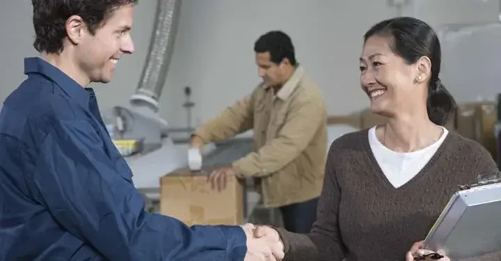 A supplier and a distributor shaking hands in a factory