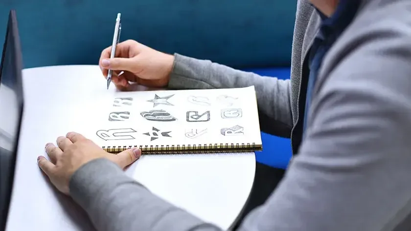 man drawing logo in notebook