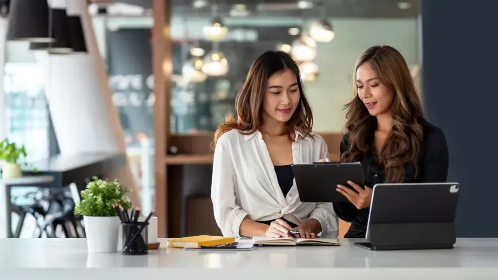 women looking at a tablet discussing capital gains tax