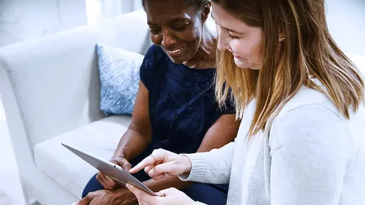 Younger woman helps senior with iPad