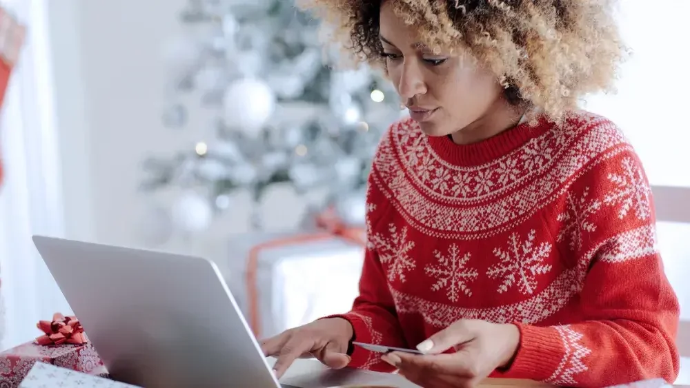 woman shopping online in a red holiday sweater 