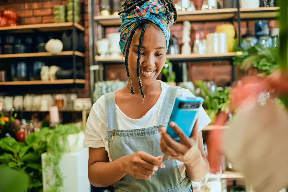 A plant shop owner in California rings up a customer using a credit card and smartphone.