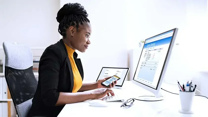 smiling-woman-sitting-at-desk-doing-online-banking