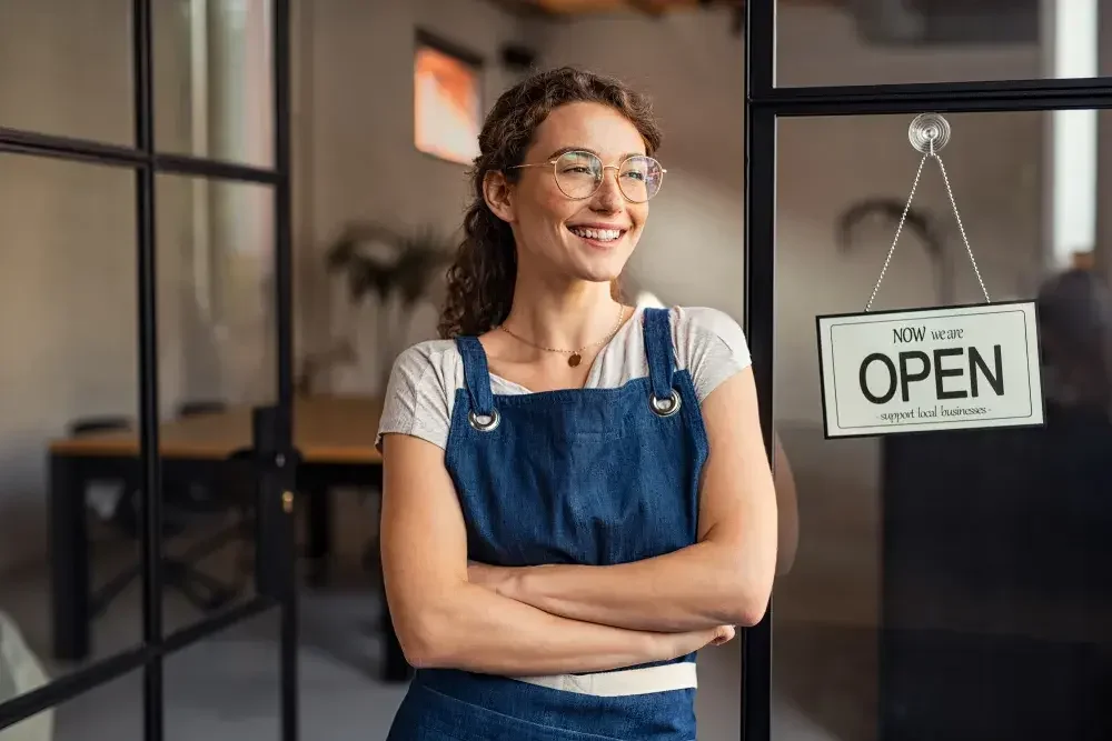 A woman in an apron standing in front of her newly opened storefront after she created her LLC with legalzoom