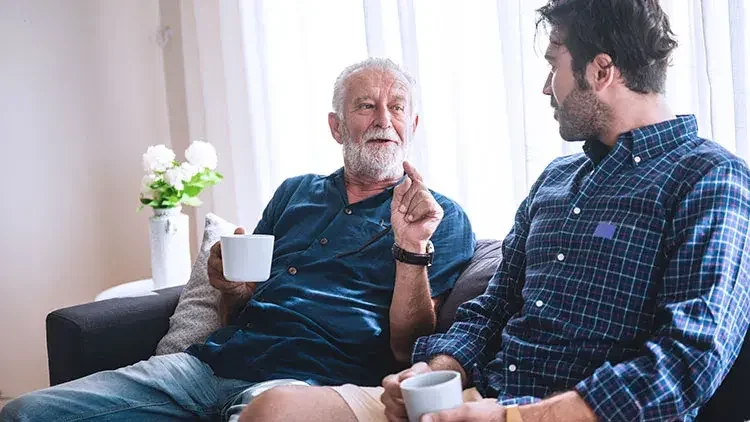 Father and son sit on sofa and have a conversation