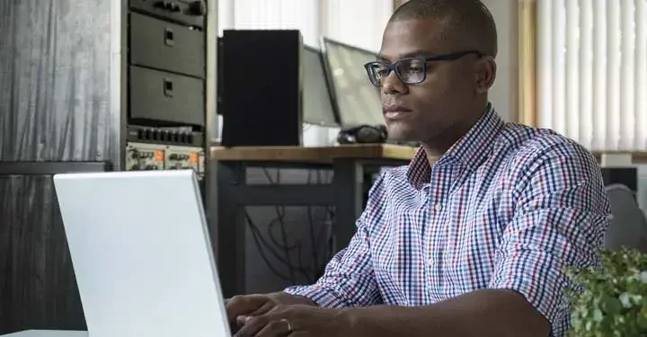 Man in music studio types on laptop