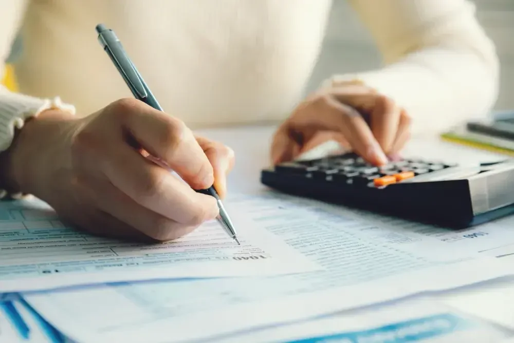 A person uses a calculator while filling out tax forms.