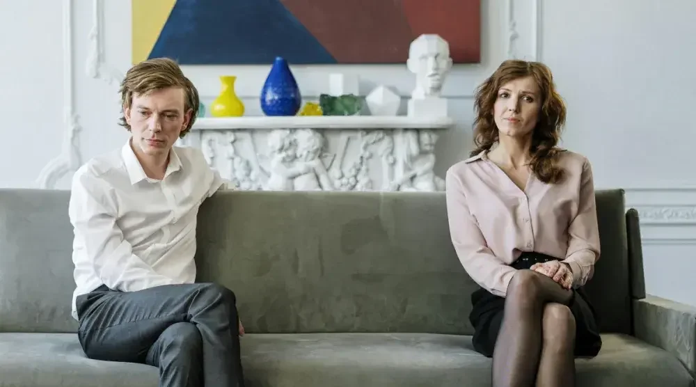 A man and a woman in Oregon sit at opposite ends of a couch as they discuss their impending divorce.