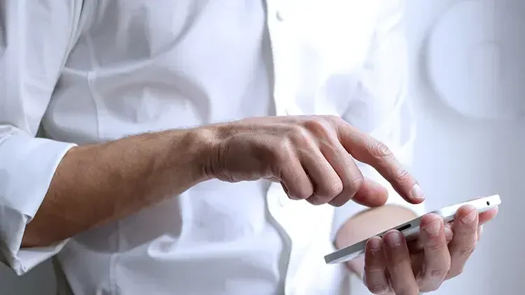 Man wearing white dress shirt taps phone