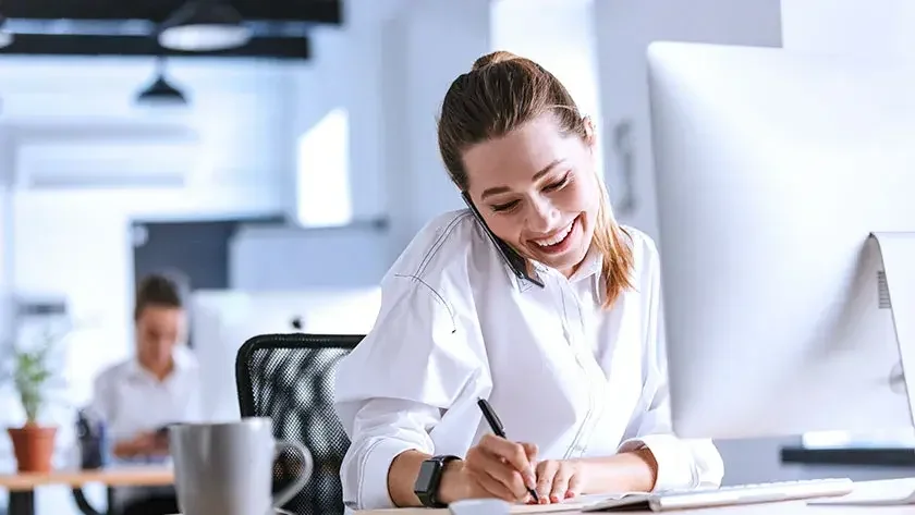 woman-writing-notes-in-office-on-phone