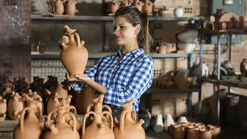 woman in blue shirt looking at pottery