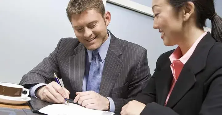 people smiling while signing paperwork