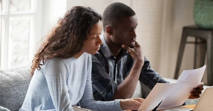 A married couple sitting on a couch reviewing divorce paperwork