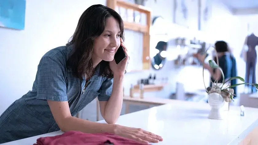 woman leaning on the counter and talking on the phone