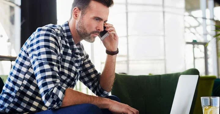 Man talking on his cellphone using his laptop