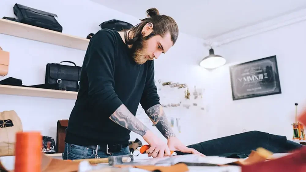 A leatherworker creates a bag for his client. Who inherits your business and its assets can be spelled out in a trust.