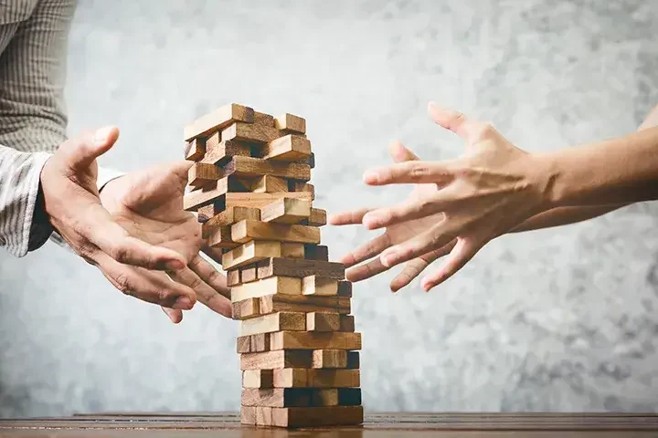 hands of 2 men playing Jenga 