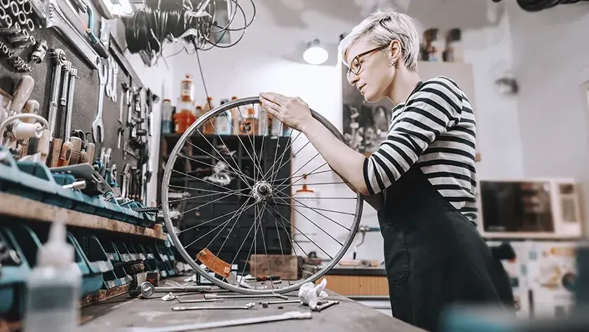 woman in striped shirt working on a bike 