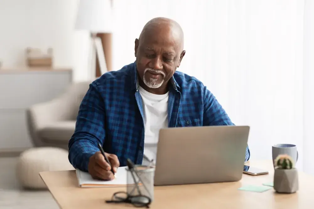 A small business owner records transactions while working from his home office.