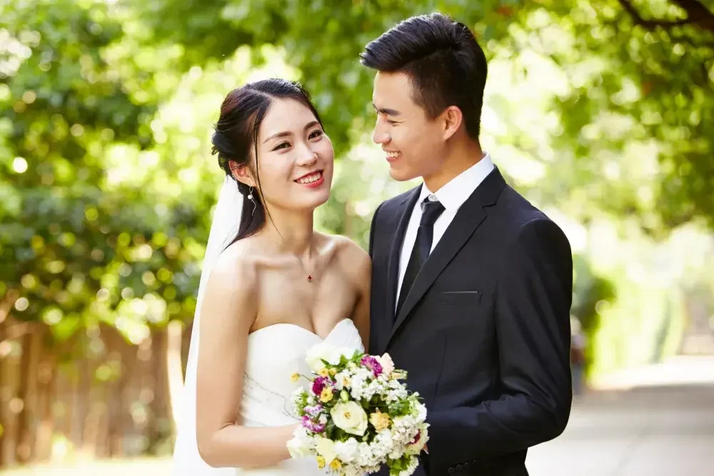 A woman and man in traditional wedding attire pose for photos. In New York, the law states that both spouses must choose to either retain their own independent lawyers OR waive their right to one in writing. 