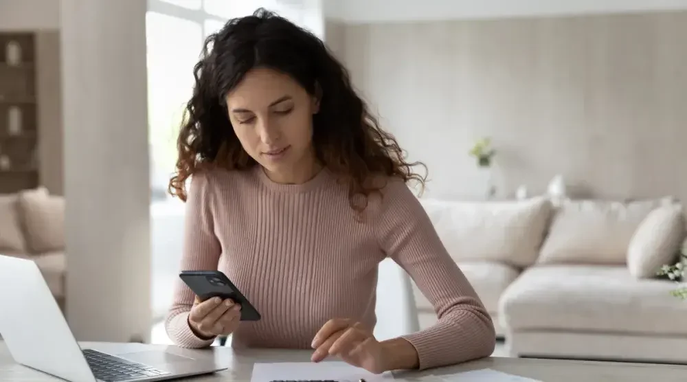 A Kansas business owner sits at her desk and performs a Kansas business search on her phone.