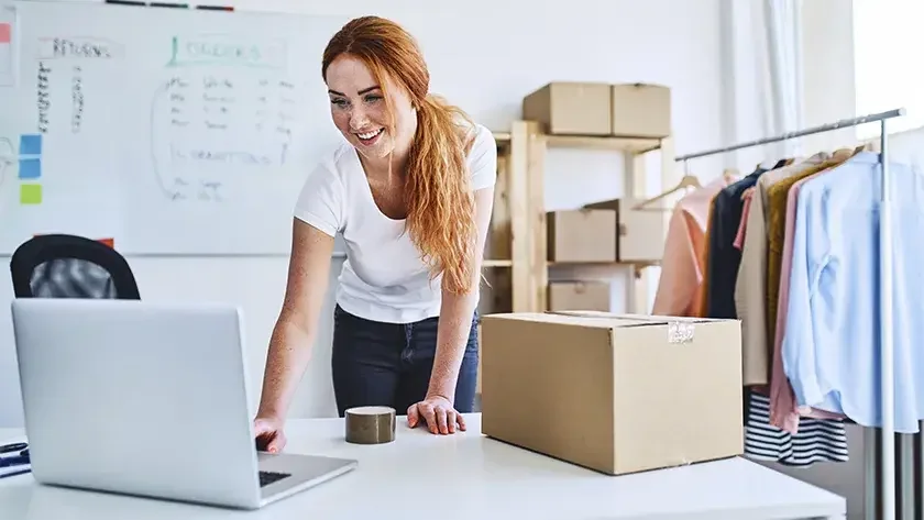 woman smiling looking at her laptop in her office