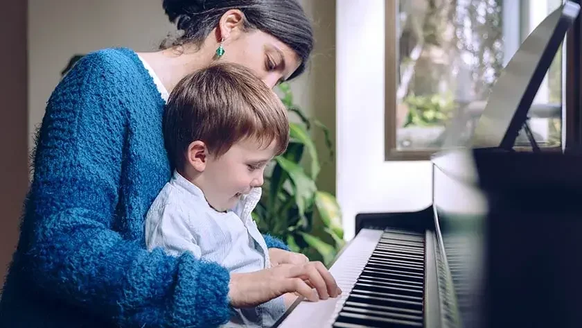 Mother holding child on lap playing piano