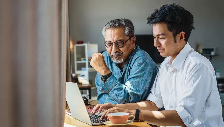 A father and son discuss what is a power of attorney as they look at the screen of a laptop computer