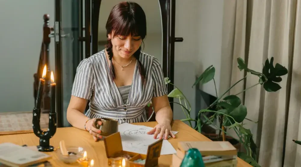 An astrologer seated at a table looks at a client's birth chart. Her small business is a sole proprietorship—an unincorporated business with only one owner who assumes unlimited liability. 