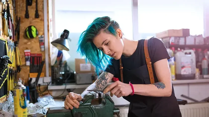 woman-with-blue-hair-working-in-hardware-shop in black shirt and suspenders