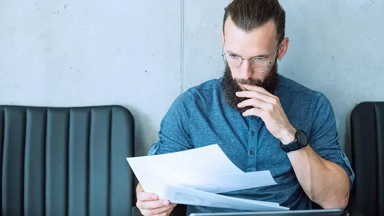 man in grey shirt reading documents 