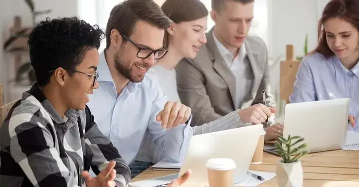 Coworkers smiling and looking at laptops together