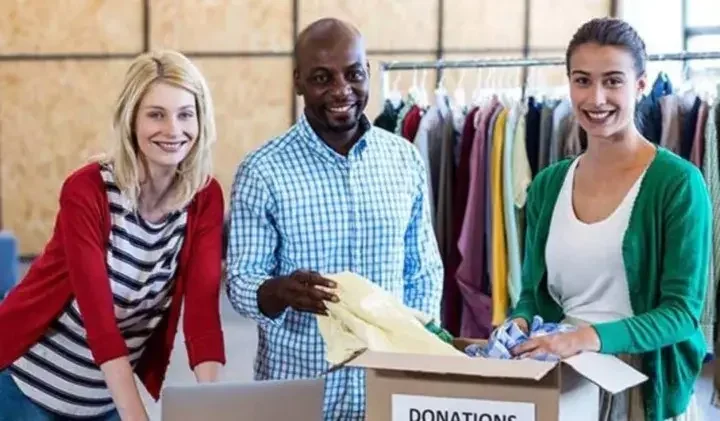 Three people standing around a box of donations