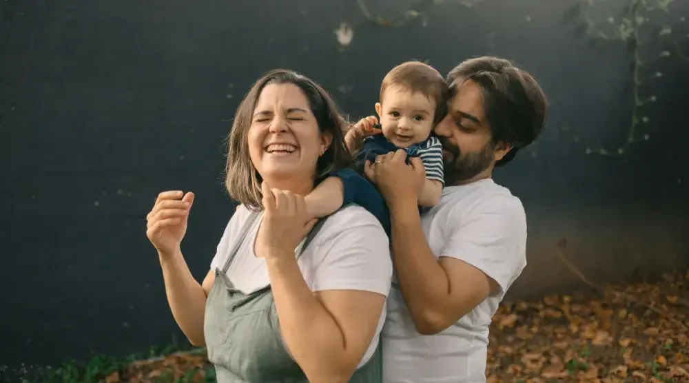 A mother in Michigan smiles and holds up her arms as her partner removes their baby from her shoulders. The couple has set up a living trust for their baby in case they die before their child becomes an adult.