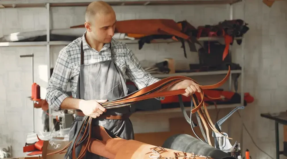 A Kentucky tanner inspects strips of leather he will use to make belts. By forming his LLC in Kentucky, he gives his business liability protection.