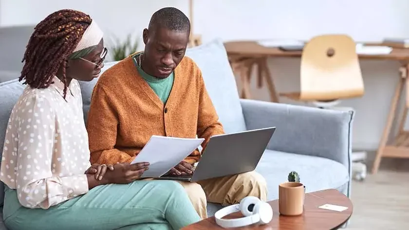 woman-helping-man-go-over-documents-typing-on-laptop looking for a registered agent