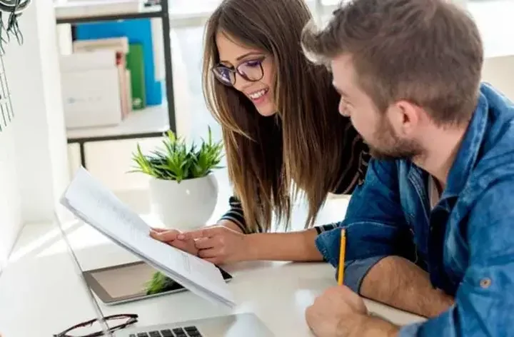 Man and woman smiling and reading a document