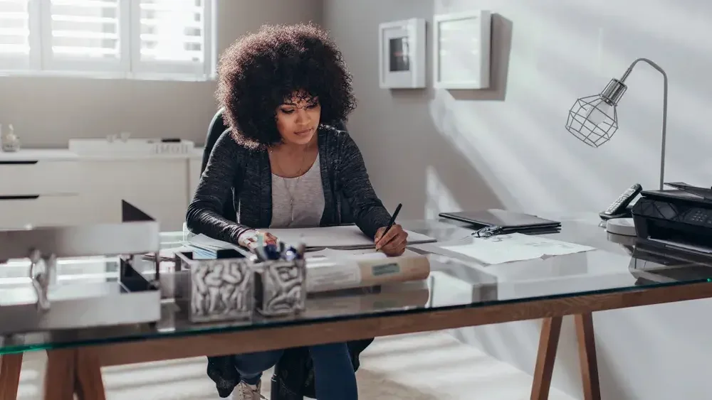 woman writing at her desk in home office