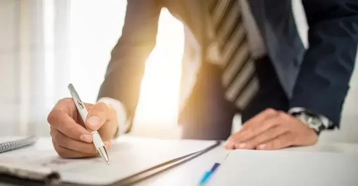 Businessman leaning over a desk, signing documents