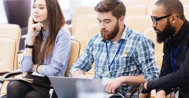 Attendees at an event working together on a laptop