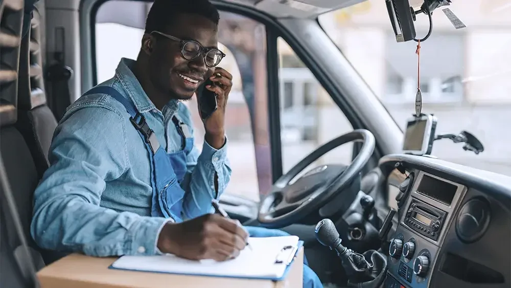 man sitting in his truck on the phone and taking notes