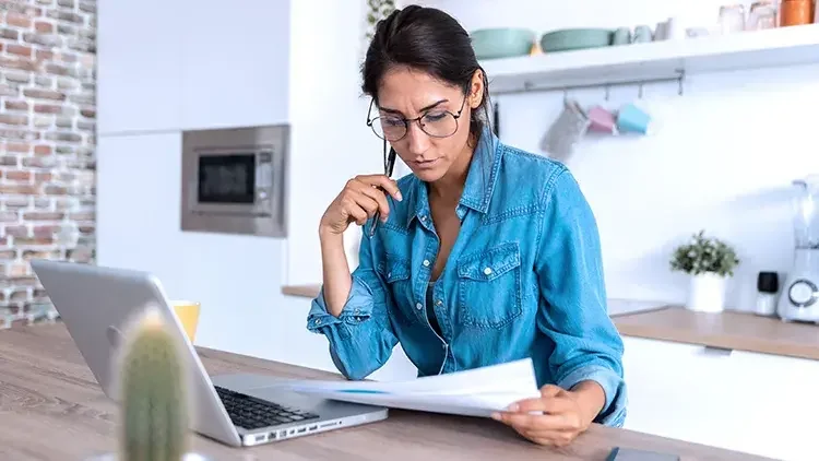 woman-examining-documents-at-home-laptop