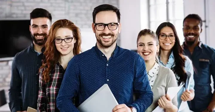 Business team in staggered triangle formation holding laptops and smiling