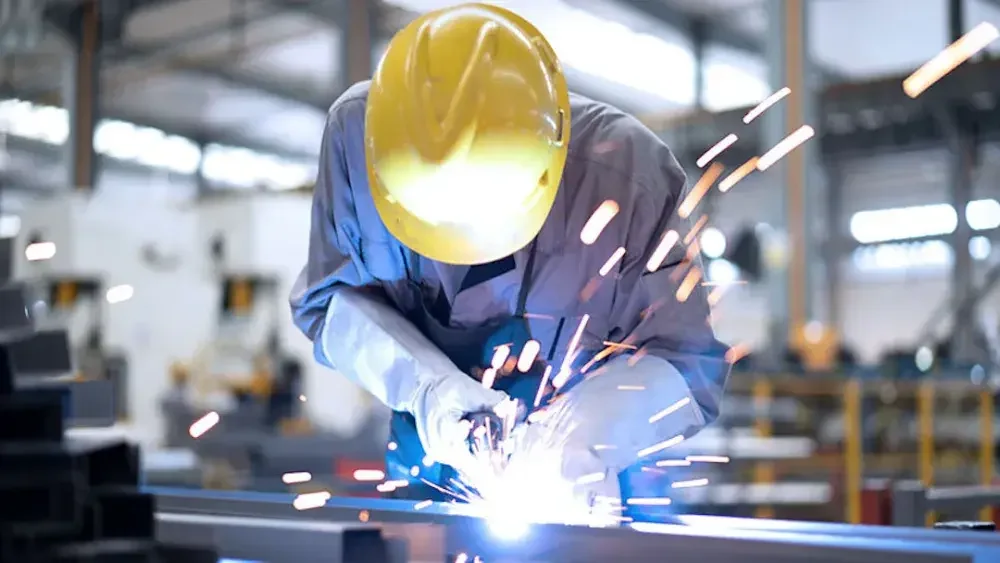 A person welds in his workshop after forming an LLC. You must register your business with your state's tax agency. 