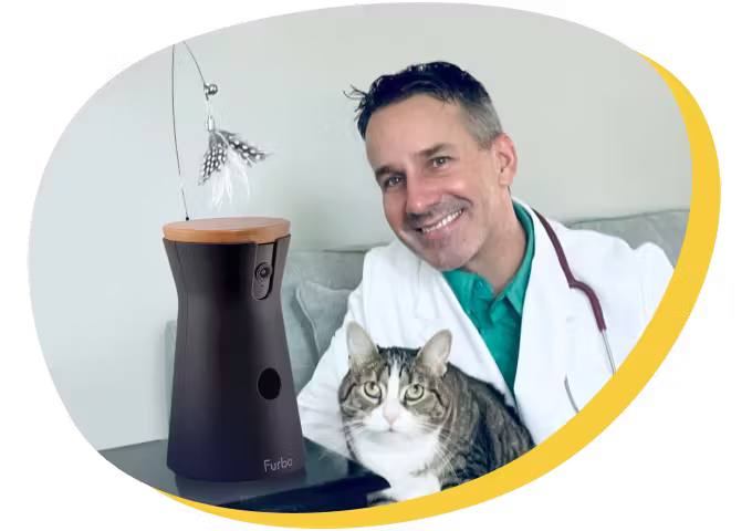 A veterinarian smiling beside a Furbo cat camera and a cat.